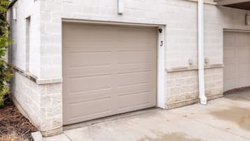 A garage door with a number '3' above it, attached to a building with a stone facade.