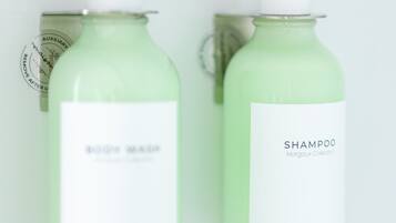 Dos botellas de líquido verde con dosificadores de bomba, una etiquetada como “AUXILIARY” y la otra como “SHAMPOO”.