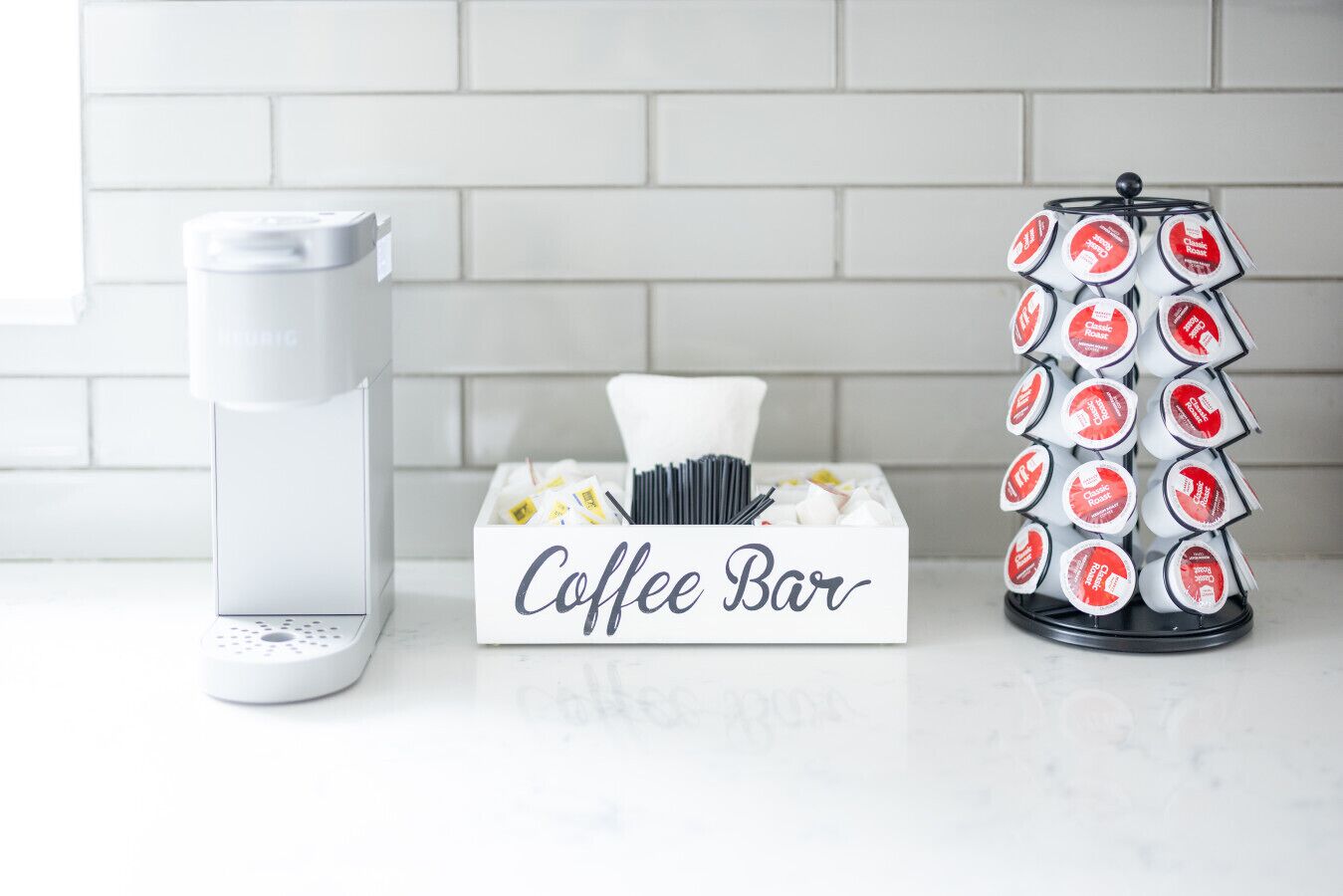 Una cafetera, un bar de café con un letrero y un dispensador de cápsulas de café.