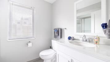 Un baño moderno con inodoro, lavamanos y espejo.