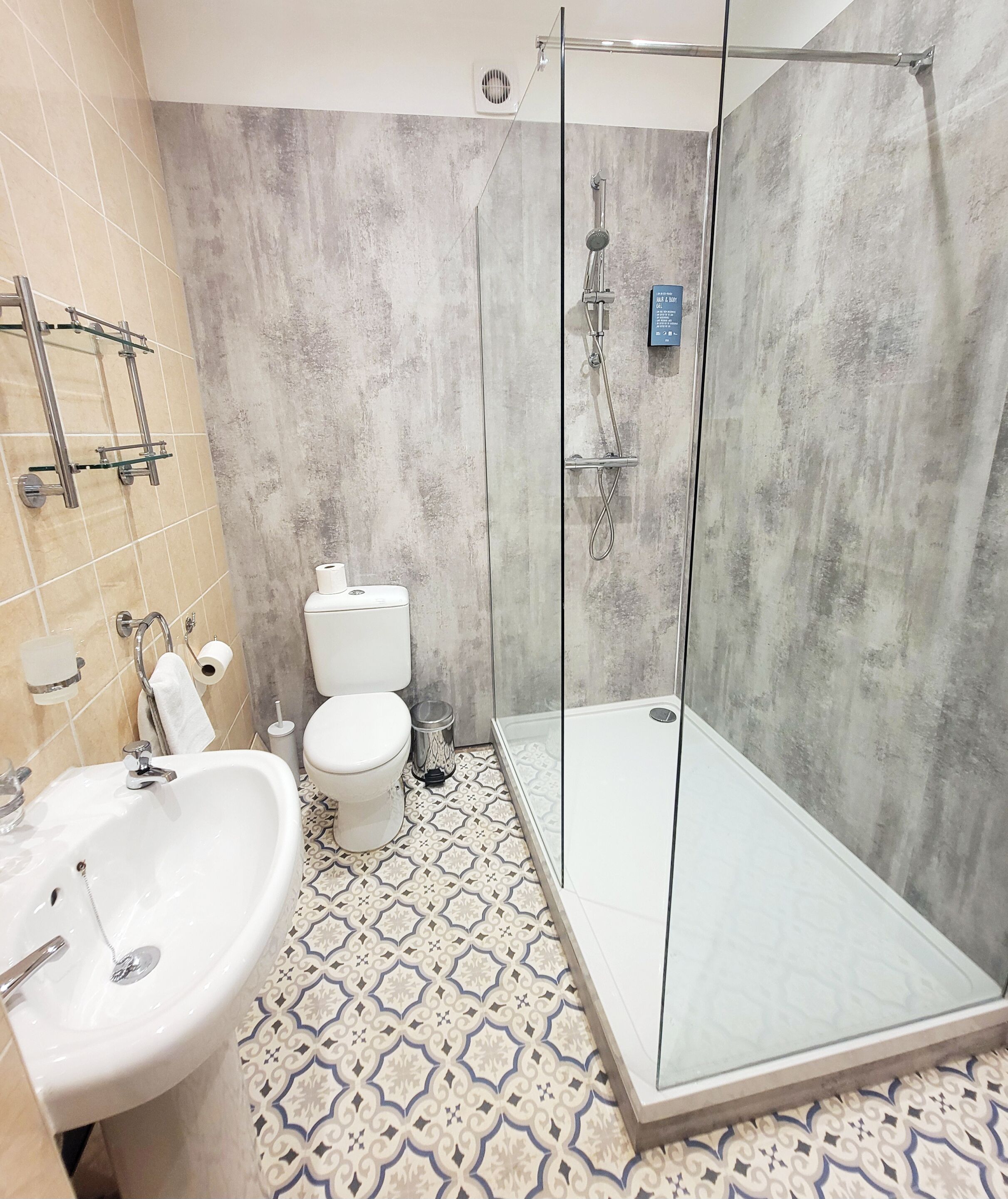 A modern bathroom with a glass-enclosed shower, a white sink, and a toilet.