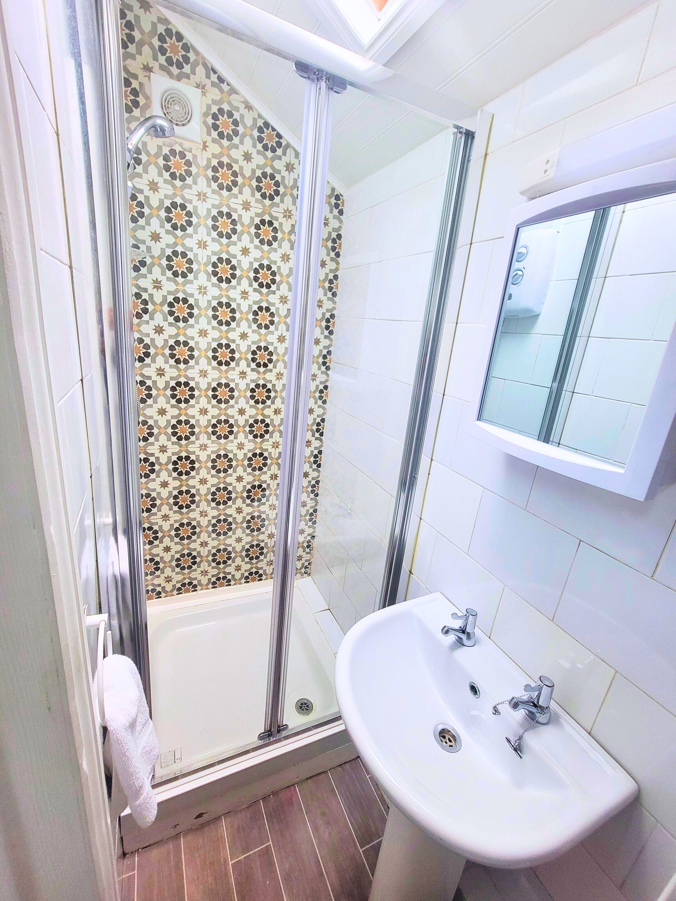 Un baño con ducha, lavamanos y espejo.