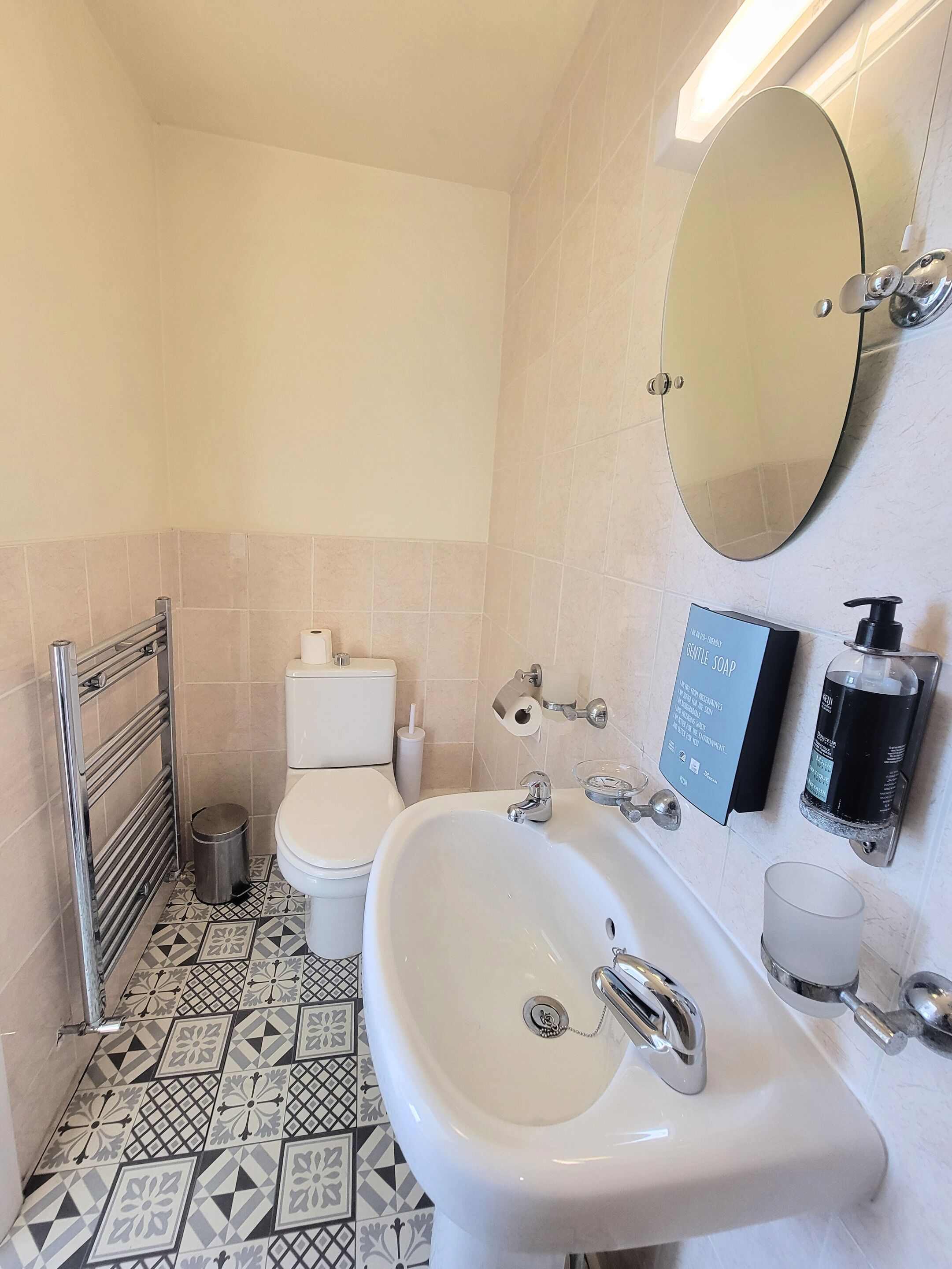 Une salle de bain avec un lavabo blanc, des toilettes, un miroir et un sèche-mains.