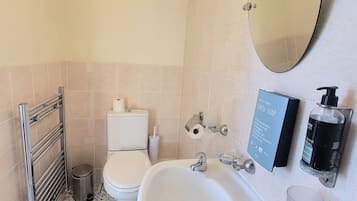 Un baño con un lavamanos blanco, un inodoro, un espejo y un secamanos.