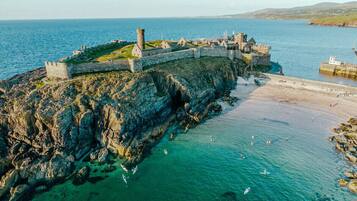 A coastal fortification with a rugged cliffside and a beach in the foreground.