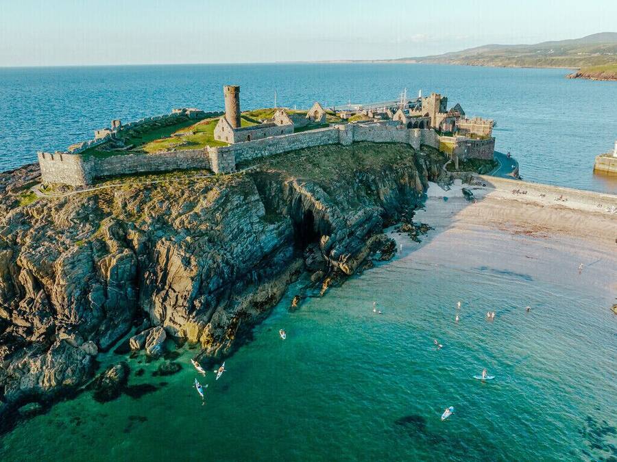 A coastal fortification with a rugged cliffside and a beach in the foreground.