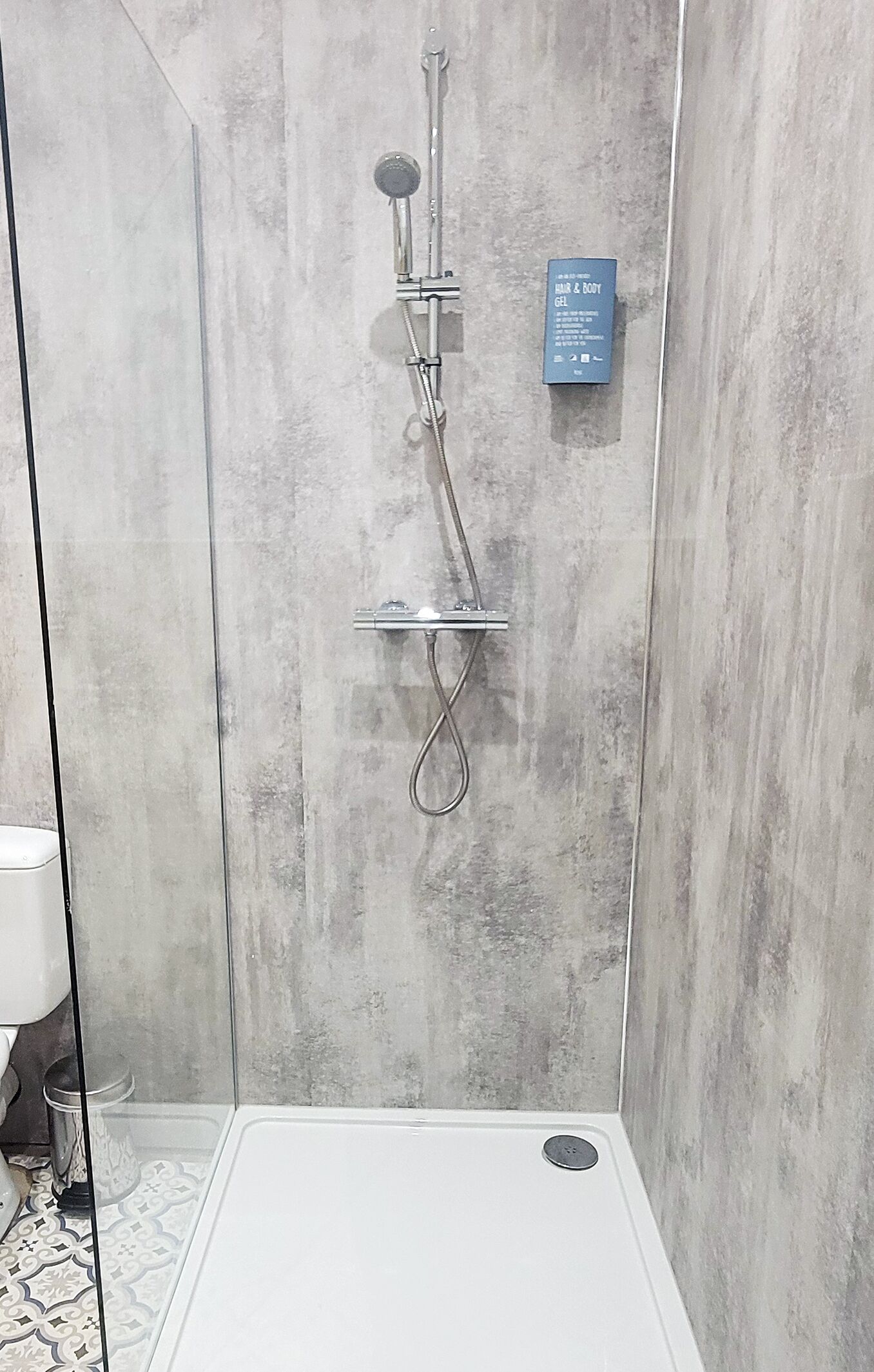 Eine Dusche mit fest installierter Bedienkonsole und Ablauf in der Bodenwanne.