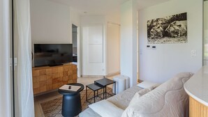 Una sala de estar moderna con una televisión de pantalla plana, un sofá, una mesita y un cuadro enmarcado en la pared.