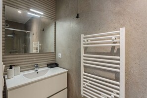 A modern bathroom with a white sink, mirror, and towel rack.