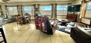 Un salon comprenant un canapé, une table à manger et des chaises, un téléviseur et de grandes fenêtres offrant une vue dégagée.