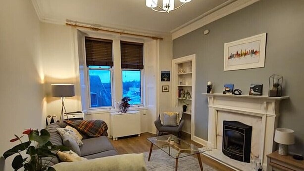 Ett mysigt vardagsrum med en öppen spis, en soffa, ett soffbord och en bokhylla.