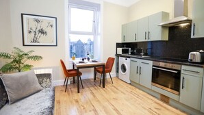 A compact living space with a dining area, a washing machine, and a kitchenette.