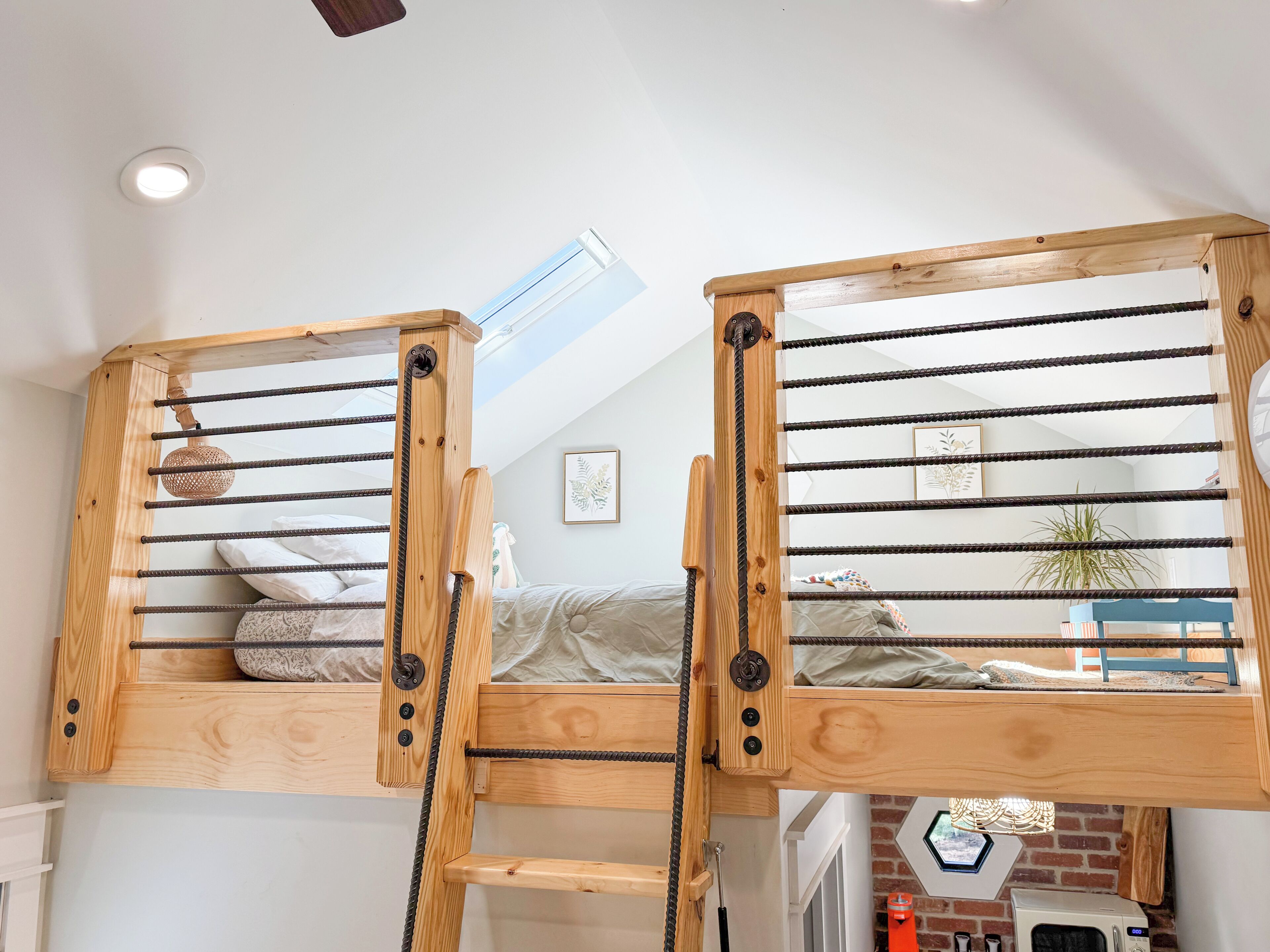 Un dormitorio estilo loft con tragaluces, literas de madera y una cocina a la vista.