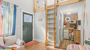 Un espacio habitable compacto con un altillo, una kitchenette y una zona de estar acogedora.