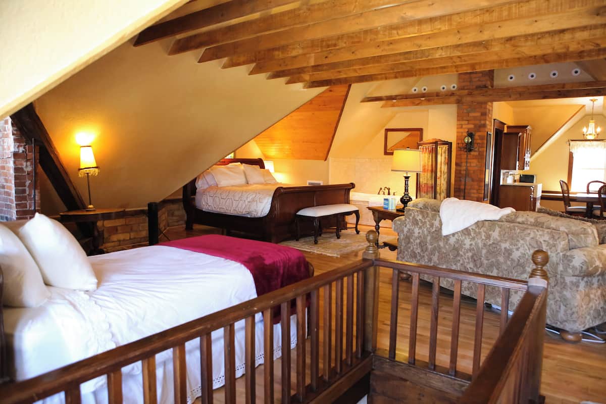 A cozy attic bedroom with a bed, a sofa, and a desk.