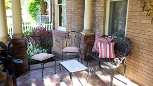 A patio with a table and two chairs, a bench with cushions, and a brick wall. - B&B on Broadway (Decorah)