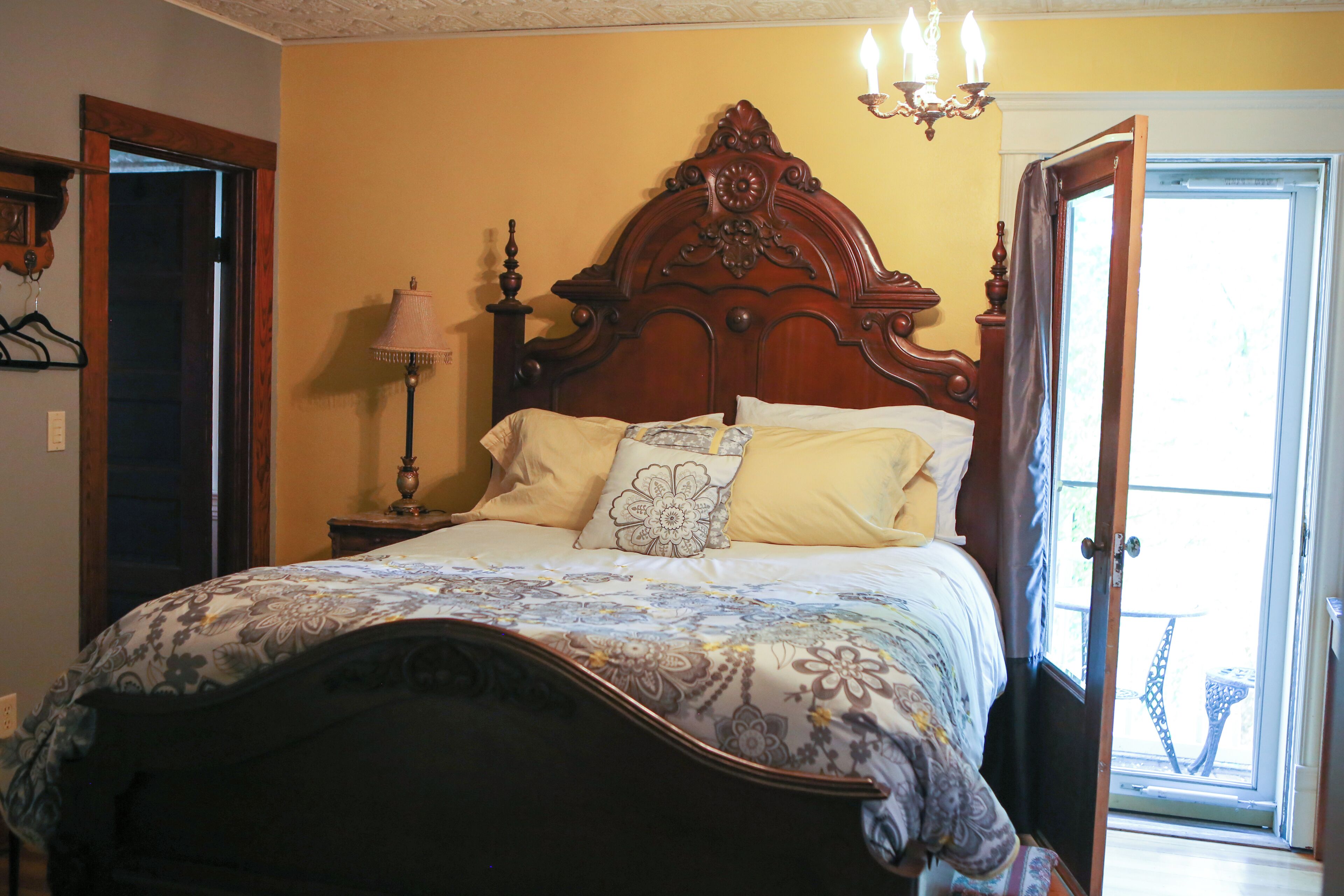 A bedroom with a large bed, a nightstand, a lamp, and a door leading to a balcony.