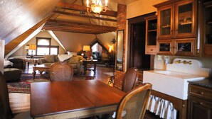 A cozy attic room with a dining table, chairs, a chandelier, and wooden cabinets. - B&B on Broadway (Decorah)