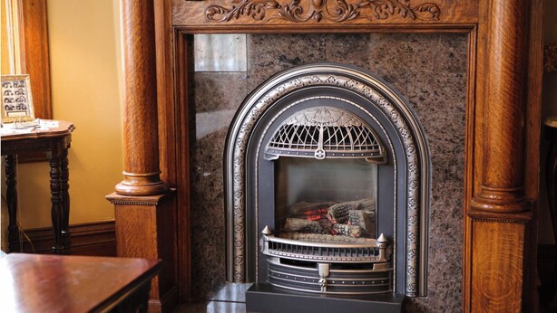 A fireplace with intricate woodwork and a stone surround. - B&B on Broadway (Decorah)