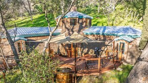 A rustic cabin with a wooden deck, a barrel, and a small porch. - Halfling House w/hot tub/firepit/more! (Coarsegold)