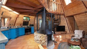 A rustic cabin interior with a kitchen, dining area, and fireplace. - Halfling House w/hot tub/firepit/more! (Coarsegold)