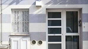Een gebouw met een grote schuifdeur, een raam met decoratieve roede's en twee kleine ronde ventilatieopeningen in de muur.