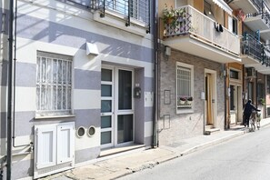 Un immeuble à plusieurs étages doté de balcons, une personne à vélo et une rue.