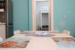 Une chambre avec un lit superposé, une table avec un set de table et un réfrigérateur.