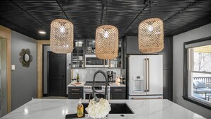 A modern kitchen with a large island, stainless steel appliances, and a view to the outside. - Secluded Retreat, Hot Tub, Fire Pit, Wildlife Views, Near New Buffalo Beach! (New Buffalo)