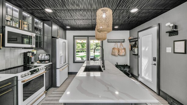 A modern kitchen with a large island, stainless steel appliances, and a unique ceiling design. - Secluded Retreat, Hot Tub, Fire Pit, Wildlife Views, Near New Buffalo Beach! (New Buffalo)