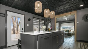 A modern kitchen with a central island, pendant lighting, and a view to the living area. - Secluded Retreat, Hot Tub, Fire Pit, Wildlife Views, Near New Buffalo Beach! (New Buffalo)