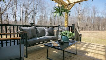 Relax in a serene outdoor seating area with a modern sofa, glass coffee table, and lush greenery.