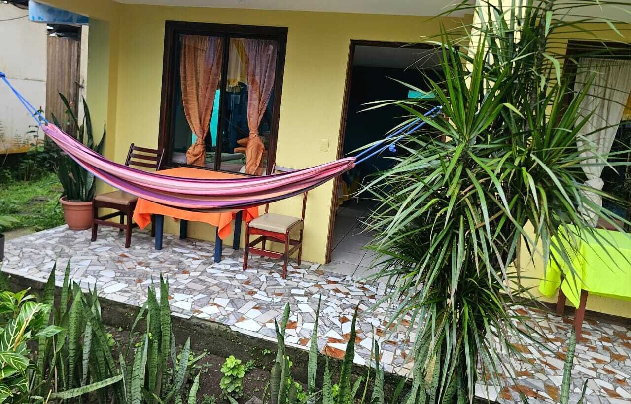 A patio with a hammock, a table, chairs, and potted plants.