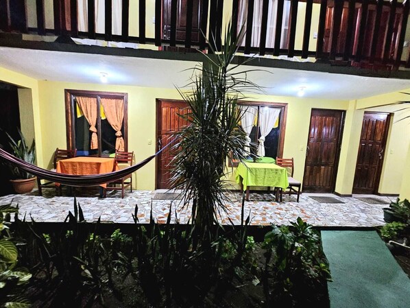 A courtyard with a hammock, a dining table with chairs, and a green tablecloth. - Cabinas Miss Miriam 2 (Colorado)