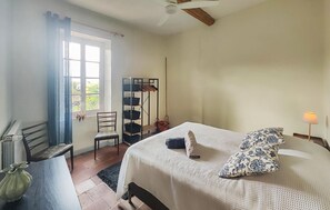 Ein Schlafzimmer mit einem Bett, einem Stuhl, einem Regal und einem Fenster.