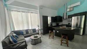 A modern kitchen with dark cabinets, stainless steel appliances, and a central island. - Rancho Matnik a Hidden Paradise (La Paz)