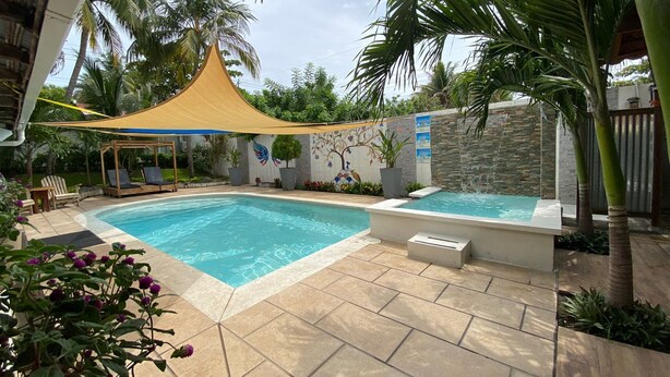 A swimming pool with a sunshade, lounge chairs, and a decorative wall. - Rancho Matnik a Hidden Paradise (La Paz)