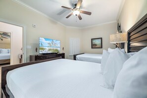 Une chambre d’hôtel avec un grand lit, un ventilateur de plafond, une télévision et une fenêtre avec des volets.