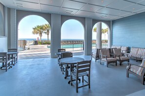 Un vaste espace extérieur aménagé avec des tables et des chaises, offrant une vue sur une piscine et une plage.