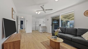 A modern living room with a grey sofa, wooden coffee table, and a ceiling fan. - 60 Beach Road, Goolwa South (Goolwa South)