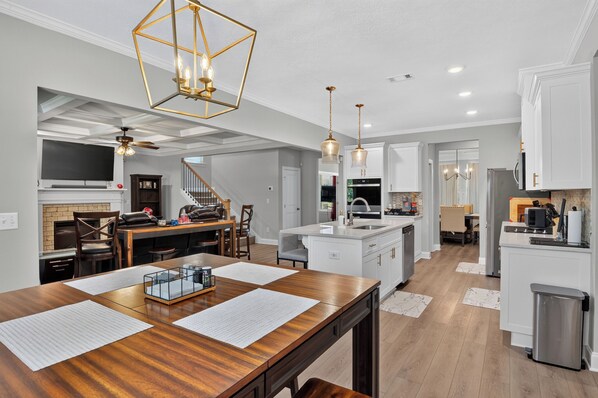 A modern kitchen with a wooden dining table, white cabinets, and a central island.