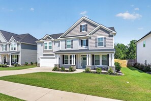 A two-story residential house with a front porch, a garage, and a well-maintained lawn.