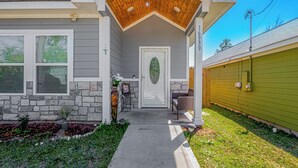 A house with a stone exterior, a wooden porch, a green garage, and a well-maintained front yard.