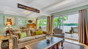 Un vaste salon doté d’une grande fenêtre donnant sur le lac Smith Mountain, et aménagé avec un canapé, des fauteuils et une table basse.