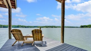 Une terrasse en bois avec deux fauteuils Adirondack donnant sur une étendue d’eau calme.