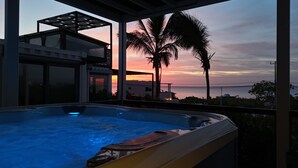 A hot tub with a sunset view, a modern building, and a palm tree. - Funnest house in Baja! Game nights w/ smart darts, shuffleboard, & video games. Enjoy a new 8 person hot tub, lounge on multiple decks w/ firepits, fast Wifi ( 250 mb+)w/ Starlink backup. Use of 2 SUPs.  Daily housekeeping optional. (El Sargento)