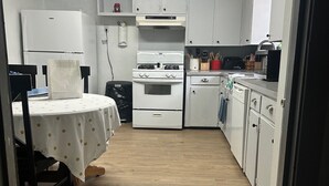 A compact kitchen with white cabinets, a white stove, and a dining table with a polka dot tablecloth. - Charming old 3-bedroom with WiFi, & central heat & air in Cabot. NEWLY Renovated (Cabot)