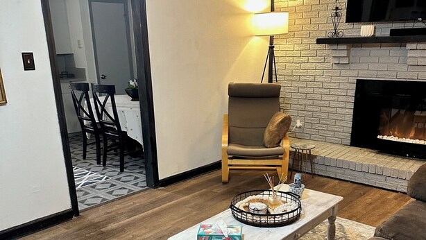 A living room with a fireplace, a coffee table with a basket, a sofa, and a dining area in the background. - Charming old 3-bedroom with WiFi, & central heat & air in Cabot. NEWLY Renovated (Cabot)