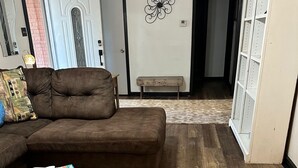 A living room with a brown sectional sofa, a coffee table with a tray and candles, a patterned rug, and a wall decoration. - Charming old 3-bedroom with WiFi, & central heat & air in Cabot. NEWLY Renovated (Cabot)