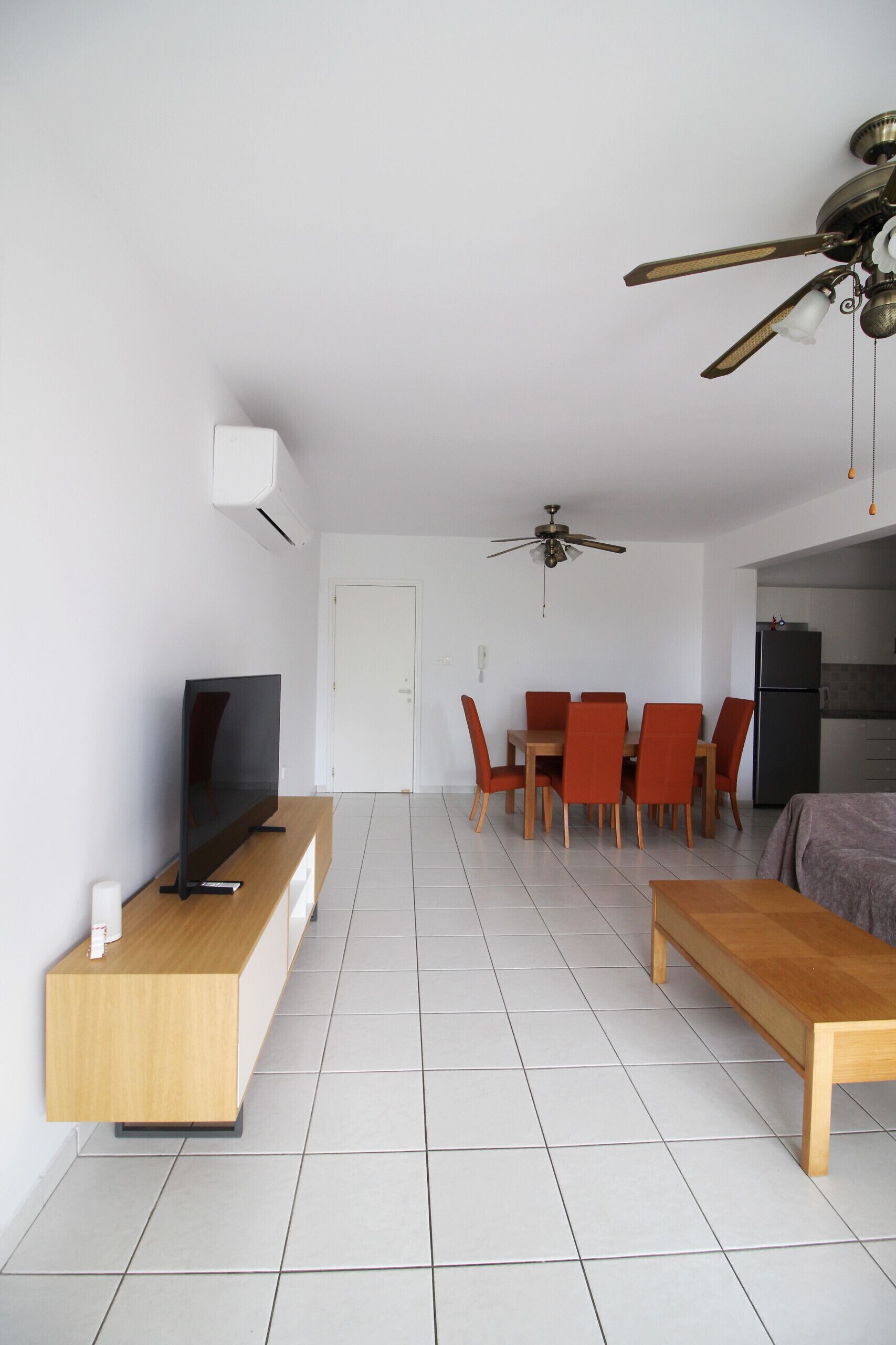 A modern living room with a TV, wooden coffee table, and a ceiling fan.